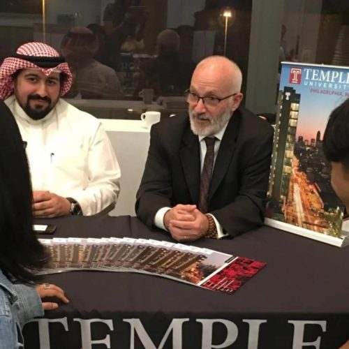 A group of people sitting around a table at a promotional event for Temple University in Philadelphia.